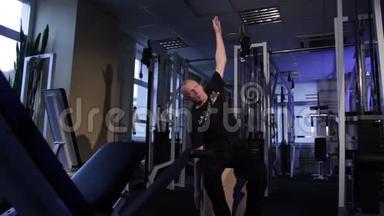 一个同龄的人在<strong>健身</strong>房里做关节体操。 手臂垂直向上抬起，躯干侧倾